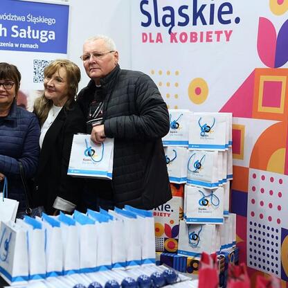 Grupa trzech osób organizuje kampanię zdrowotną przed Silesia Stadium, promując profilaktykę zdrowotną i edukację. (wygenerowano przez AI)