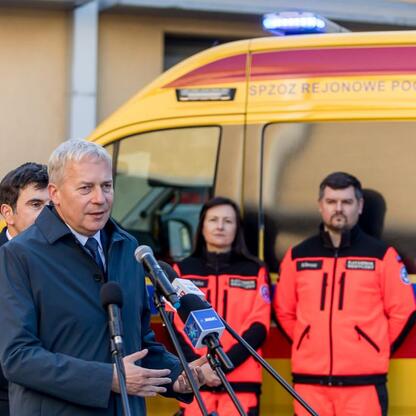 Marszałek Wojciech Saługa przemawia na uroczystości dostawy nowoczesnych ambulansów. (wygenerowano przez AI)
