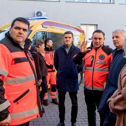 Wojciech Saługa, Marszałek Województwa Śląskiego, omawia nowe ambulanse z wojewodą Markiem Wójcikiem i posłami. (wygenerowano przez AI)