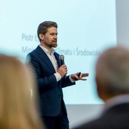 Na konferencji wojewódzkiej o poprawie jakości powietrza w Śląsku, uczestnik prezentuje strategie redukcji emisji zanieczyszczeń. (wygenerowano przez AI)