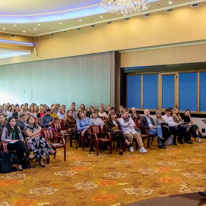 Konferencja o poprawie jakości powietrza w Śląsku, uczestnicy w strojach formalnych, sala z chandelierami i dywanem. (wygenerowano przez AI)