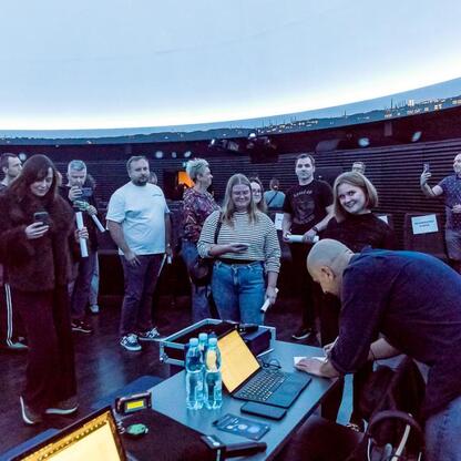 Wśród 280 słuchaczy w Planetarium Śląskiego, widoczna grupa osób przygotowuje się do transmisji audycji 