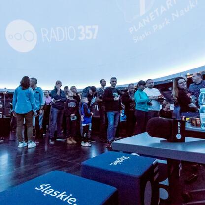 Wśród tłumu słuchaczy w Planetarium Śląskiego rozbrzmiewa muzyka z Radio 357, podczas notowania listy piosenek. (wygenerowano przez AI)