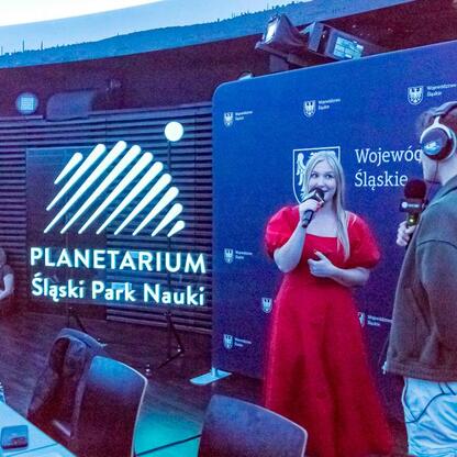 Na scenie w Planetarium Śląskiego trwa koncert Radio 357, z udziałem Członkini Zarządu Województwa Śląskiego, Joanna Bojczuk. (wygenerowano przez AI)