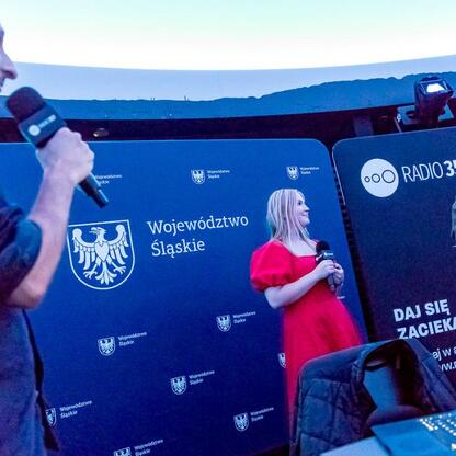 Joanna Bojczuk, członek zarządu Województwa Śląskiego, prowadzi audycję na żywo z Planetarium Śląskiego. (wygenerowano przez AI)