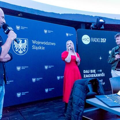 Joanna Bojczuk, Członek Zarządu Województwa Śląskiego, w centrum, podczas transmisji z Planetarium Śląskiego. (wygenerowano przez AI)