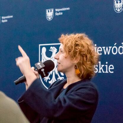 Podczas transmisji z Planetarium Śląskiego prowadzona jest rozmowa z gośćmi, w tle logo województwa śląskiego. (wygenerowano przez AI)