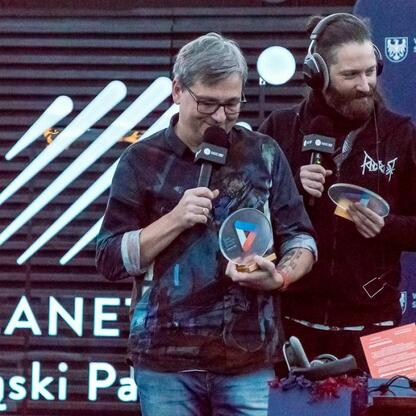 Zdjęcie przedstawia moment z transmisji Radio 357 z Planetarium Śląskiego, gdzie Mateusz Fusiarz i Marcin Łukawski prowadzą audycję, omawiając muzykę i astronomię. (wygenerowano przez AI)