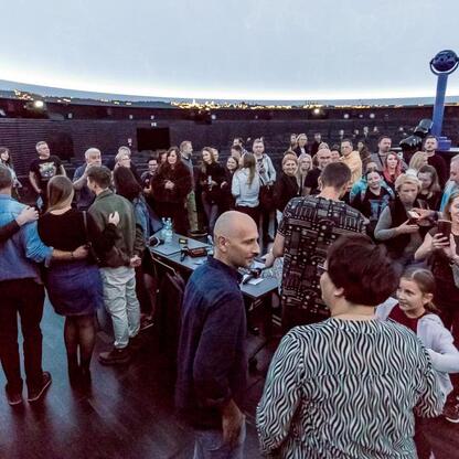 Ludzie cieszą się koncertem w Planetarium Śląskiego, podczas transmisji 208. notowania listy piosenek Radio 357. (wygenerowano przez AI)