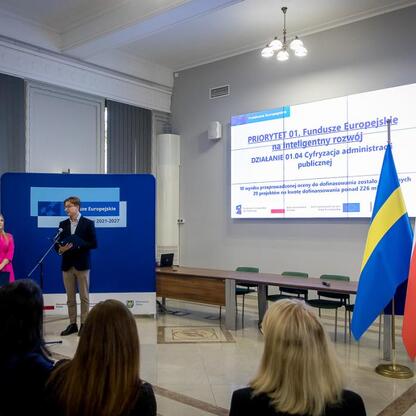 Formalna prezentacja w konferencyjnym pomieszczeniu, związana z projektem europejskim na inteligentny rozwój. (wygenerowano przez AI)