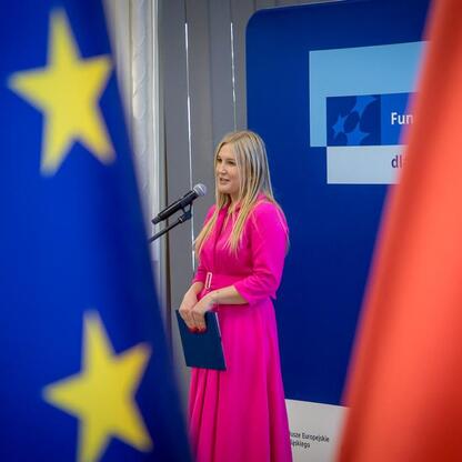 Członkini Zarządu Województwa Śląskiego, Joanna Bojczuk, przemawia na podium podczas konferencji o rozdaniu funduszy europejskich. (wygenerowano przez AI)