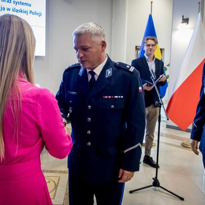 Wicemarszałek Grzegorz Boski i Joanna Bojczuk wręczają listy gratulacyjne beneficjentom projektów z Unii Europejskiej w Urzędzie Marszałkowskim Województwa Śląskiego. (wygenerowano przez AI)