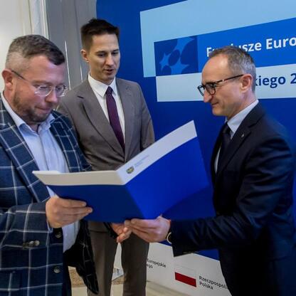 Wicemarszałek Grzegorz Boski wręcza listy gratulacyjne przedstawicielom beneficjentów projektów finansowanych ze środków europejskich w Silesia 2021-2027. (wygenerowano przez AI)