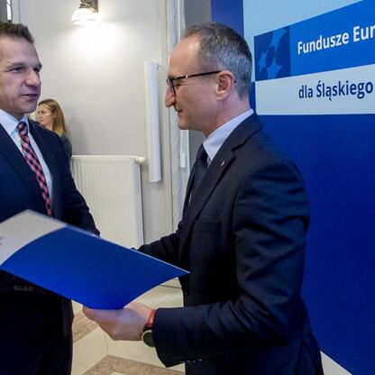 Grzegorz Boski i Joanna Bojczuk wręczają listy gratulacyjne za sukcesy w projekcie Funduszy Europejskich dla Śląska 2021-2027. (wygenerowano przez AI)