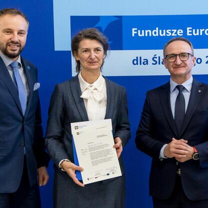 Grzegorz Boski i dwaj współpracownicy wręczają listy gratulacyjne w ramach projektu Fundusze Europejskie dla Śląska 2021-2027. (wygenerowano przez AI)