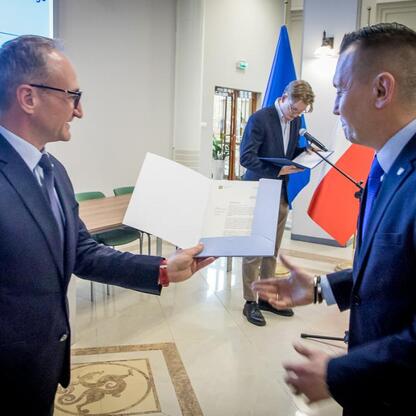 Grzegorz Boski i Marcin Ryś wicemarszałkowie Województwa Śląskiego wręczają listy gratulacyjne przedstawicielom beneficjentów projektów dofinansowanych ze środków europejskich. (wygenerowano przez AI)