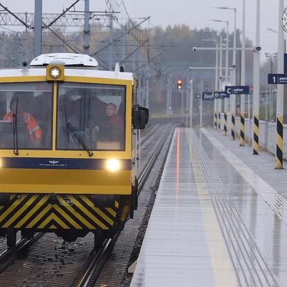 Na stacji kolejowej widoczny jest żółto-biały pojazd utrzymywania torów, który prawdopodobnie jest używany do inspekcji i naprawy torów kolejowych. (wygenerowano przez AI)