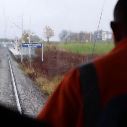 Zdjęcie przedstawia widok z pociągu na torze kolejowym i platformę stacji Pawłowice Śląskie Centrum. (wygenerowano przez AI)