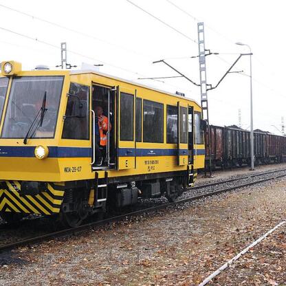 Zdjęcie przedstawia żółto-niebieski lokomotywę WDA-29-07 z PKP, ciągnącą pociąg towarowy na torach kolejowych w stacji lub wąskim torowisku. (wygenerowano przez AI)