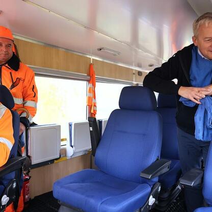 Wojciech Saługa, Marszałek Województwa Śląskiego, prowadzi rozmowę z wiceministrem infrastruktury Piotrem Malepszakiem w pociągu, omawiając reaktywację linii kolejowej Katowice-Jastrzębie. (wygenerowano przez AI)