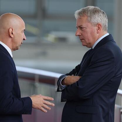 Dwa mężczyźni w garniturach dyskutują podczas konferencji o bezpieczeństwie i odporności cywilnej i gospodarczej. (wygenerowano przez AI)