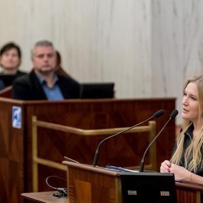 W trakcie sesji Młodzieżowego Sejmiku Województwa Śląskiego, młoda kobieta przemawia z podium, podkreślając znaczenie upamiętniania Tragedii Górnośląskiej. (wygenerowano przez AI)