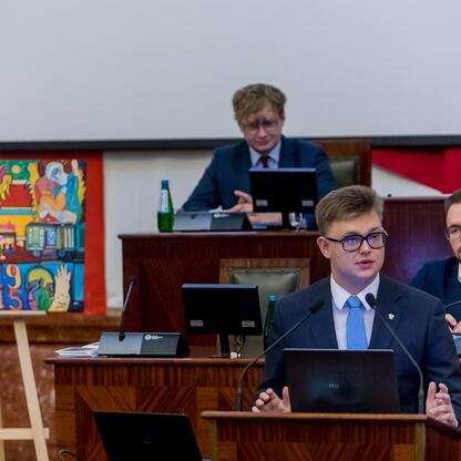 Formalna sesja Młodzieżowego Sejmiku Województwa Śląskiego, gdzie parlamentarzyści dyskutują nad upamiętnieniem Tragedii Górnośląskiej. (wygenerowano przez AI)