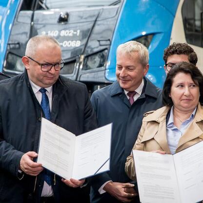 Oficjalna sesja podpisu umowy o wsparcie dla pracowników odchodzących z branży górniczej, realizowana przez Polską Grupę Górniczą, Koleje Śląskie i Synercom Usługi Wspólne, z udziałem marszałka Wojcie (wygenerowano przez AI)