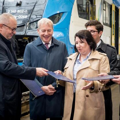 Oficjalna sesja podpisania porozumienia o wsparciu dla pracowników odchodzących z branży górniczej, realizowana przez Koleje Śląskie, Polską Grupę Górniczą i Synercom Usługi Wspólne, z udziałem Wojcie (wygenerowano przez AI)