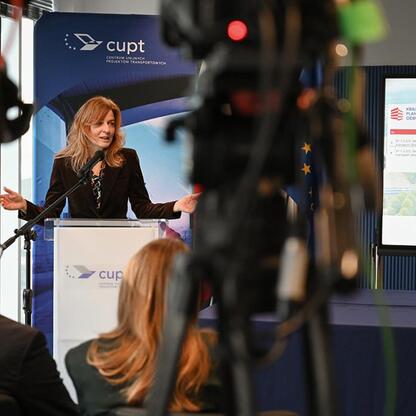 Kobieta przemawia na konferencji prasowej, prezentując plan odbudowy i finansowanie zakupu nowych pociągów dla Kolei Śląskich. (wygenerowano przez AI)