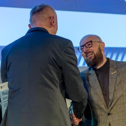 Podczas ceremonii wręczenia nagród za najlepszą przestrzeń publiczną Województwa Śląskiego, wicemarszałek Leszek Pietraszek prezentuje wyróżnienie laureatom konkursu. (wygenerowano przez AI)