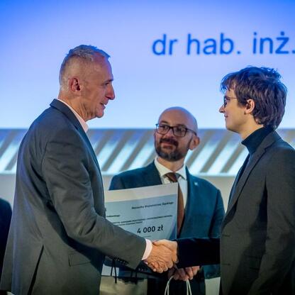 Wicemarszałek Leszek Pietraszek wręcza nagrodę laureatom konkursu Najlepsza Przestrzeń Publiczna Województwa Śląskiego. (wygenerowano przez AI)