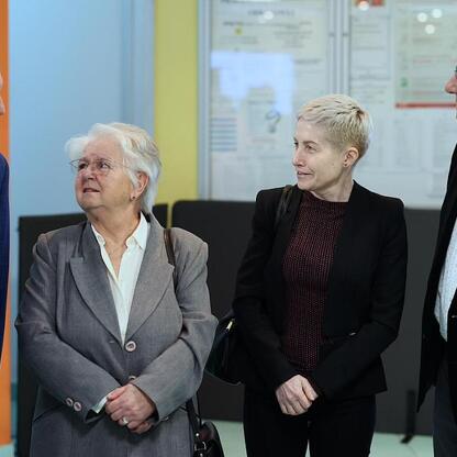 Zdjęcie przedstawia czterech osób w profesjonalnym ujęciu, związanych z nowoczesnymi technologiami w leczeniu nowotworów, zwłaszcza radioterapią adaptacyjną. (wygenerowano przez AI)