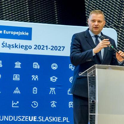 Członek Zarządu Województwa Śląskiego Rafał Adamczyk przemawia na konferencji o Europejskich Funduszach dla Śląska 2021-2027. (wygenerowano przez AI)