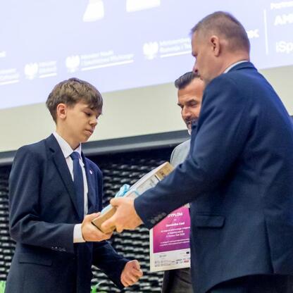 Młody uczeń odbiera nagrodę na konferencji edukacyjnej w Katowicach, wspieranej przez Europejskie Fundusze dla Śląska. (wygenerowano przez AI)