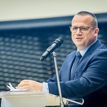 Na konferencji o motywacji i determinacji w edukacji, na podium stoi Marcin Ryś, prezentujący projekt Funduszy Europejskich dla edukacji w Śląsku. (wygenerowano przez AI)