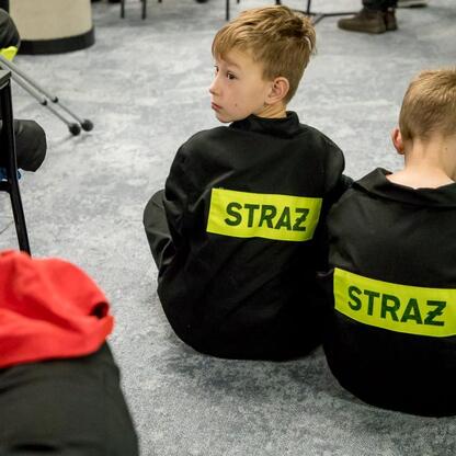Dwa chłopcy w czarnych kurtkach z napisem 