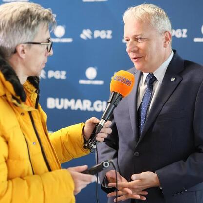 Marszałek Wojciech Saługa w rozmowie z dziennikarzem przedstawia potencjał regionu Śląska jako centrum przemysłu obronnego. (wygenerowano przez AI)