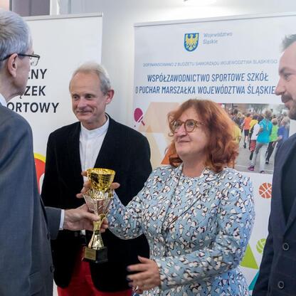 Przedstawiciele Sejmiku Województwa Śląskiego wręczają trofea zwycięzcom sportowego współzawodnictwa szkół. (wygenerowano przez AI)