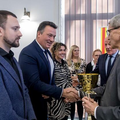 Oficjalna uroczystość w Urzędzie Marszałkowskim, gdzie radni wręczają trofea zwycięzcom sportowych zawodów szkół województwa śląskiego. (wygenerowano przez AI)