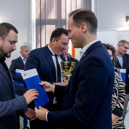 Przedstawiciele Sejmiku Województwa Śląskiego wręczają nagrody zwycięzcom sportowego konkursu szkół. (wygenerowano przez AI)