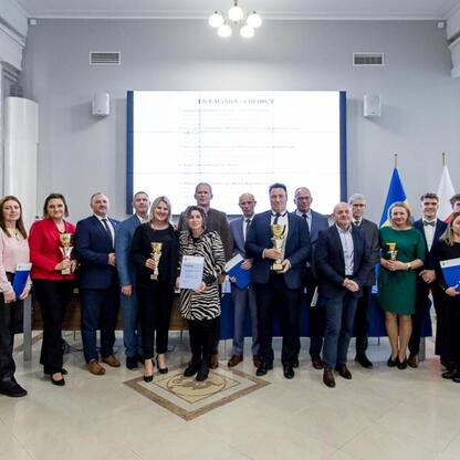 Grupa osób uczestniczących w ceremonii wręczenia nagród za sukcesy w sportowej rywalizacji szkół województwa śląskiego. (wygenerowano przez AI)