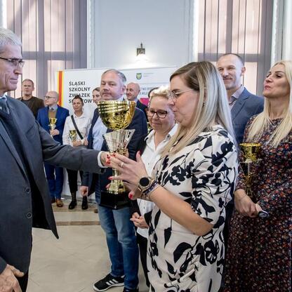 Przedstawiciele Śląskiego Szkolnego Związku Szkoł odbierają nagrody za sukcesy w sportowym turnieju. (wygenerowano przez AI)