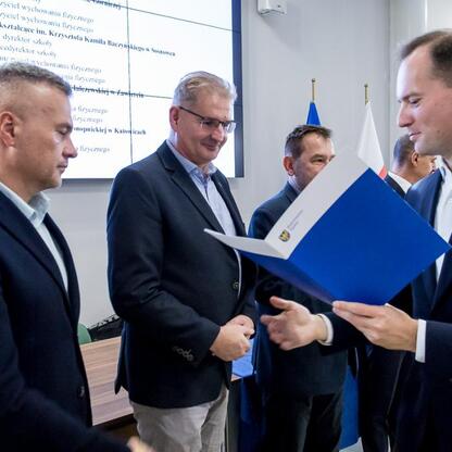 Wojewódzka gala sportowa w Silesia Voivodeship Marshal's Office, gdzie przedstawiciele zwycięskich szkół odbierają nagrody za sukcesy w sportach szkolnych. (wygenerowano przez AI)