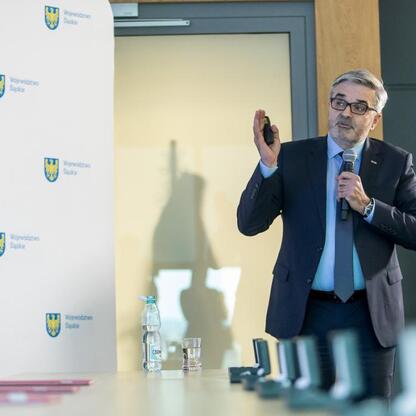 Mężczyzna w garniturze prowadzi prezentację w sali konferencyjnej Województwa Śląskiego. (wygenerowano przez AI)