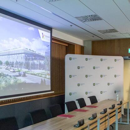 Mężczyzna w garniturze przemawia na konferencji w Katowicach, prezentując rozwój lotniska. (wygenerowano przez AI)