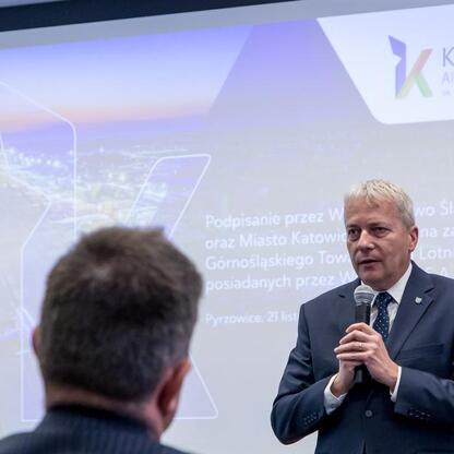 Marszałek Wojciech Saługa przemawia na konferencji o przejęciu kontrolnej większości w Katowice Airport. (wygenerowano przez AI)