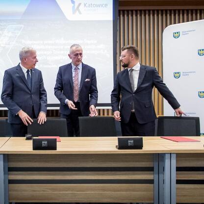 Wojciech Saługa i Leszek Pietraszek podpisują umowę o przejęciu akcji w Katowice Airport. (wygenerowano przez AI)