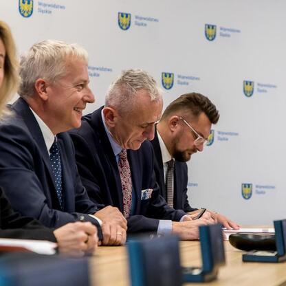 Wojciech Saługa i Leszek Pietraszek podpisują umowę o przejęciu kontroli nad Katowice Airport. (wygenerowano przez AI)