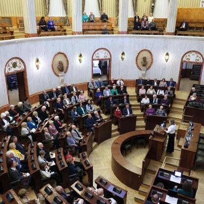 Wnętrze Sali Sejmowej Śląskiej, gdzie odbyła się pierwsza edycja Śląskiego Konwentu Rad Seniorów. Uczestnicy, w tym Rafał Adamczyk i Ewa Kołodziej, omawiają role i wyzwania seniorów. (wygenerowano przez AI)